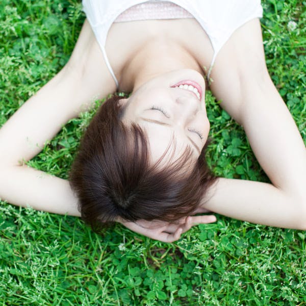 Young woman lying in the grass enjoying the sun. 