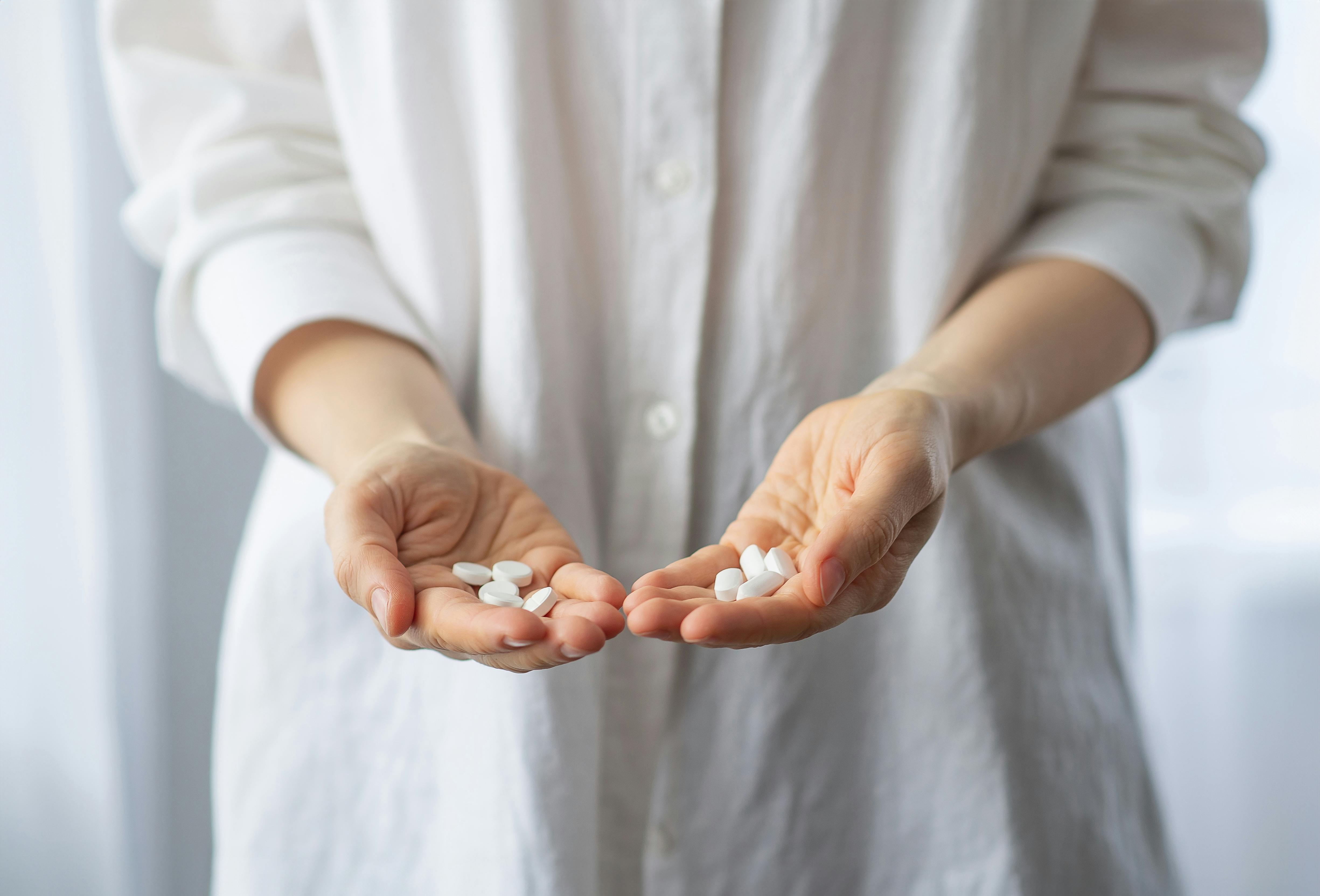 Person holding supplement pills in two hands