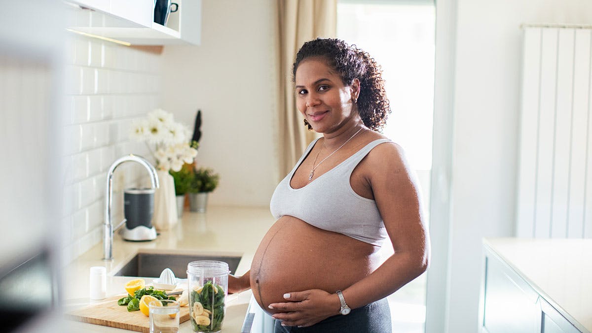 Pregnant Hispanic woman preparing salad