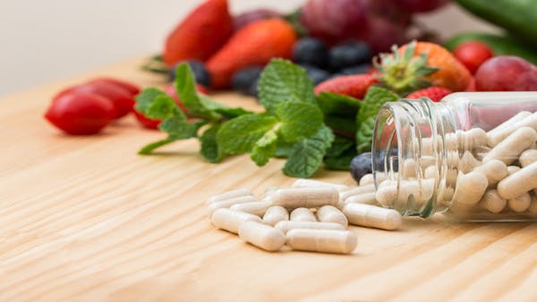 Close-up of vitamin supplements in a clear bottle on a wooden table