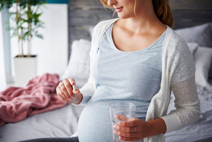 pregnant woman taking folic acid supplement