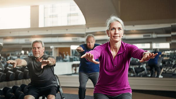 Mature group of men and women exercising at gym