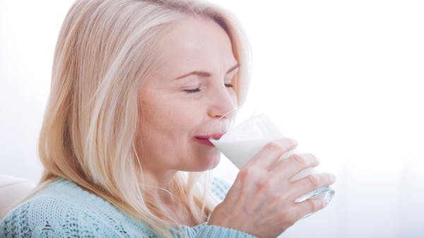 Older woman drinks a glass of milk