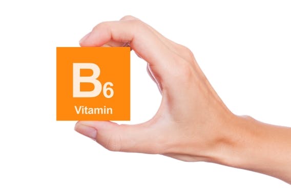 A hand holds an orange card with the text “B6 Vitamin”
