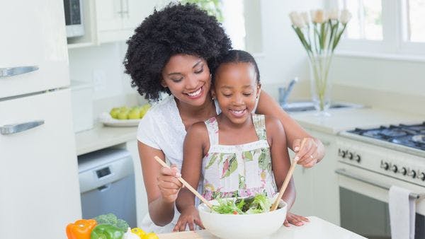 Mother and daughter making salad together in the kitchen