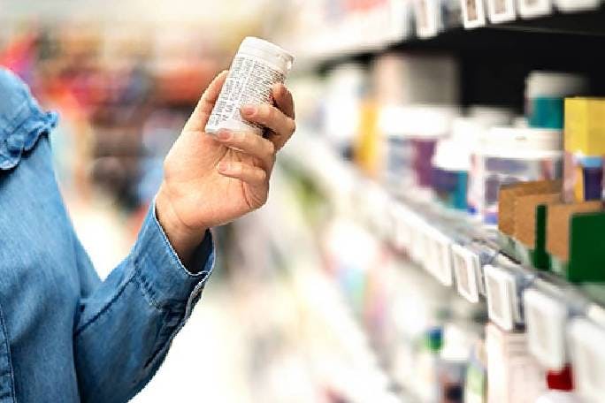 customer in pharmacy holding medicine bottle