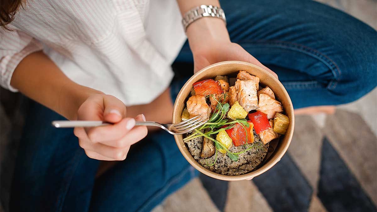 woman holding a bowl of salmon and rice