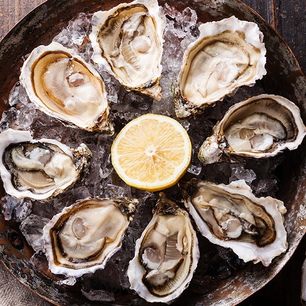 A circle of oysters around a lemon slice on ice
