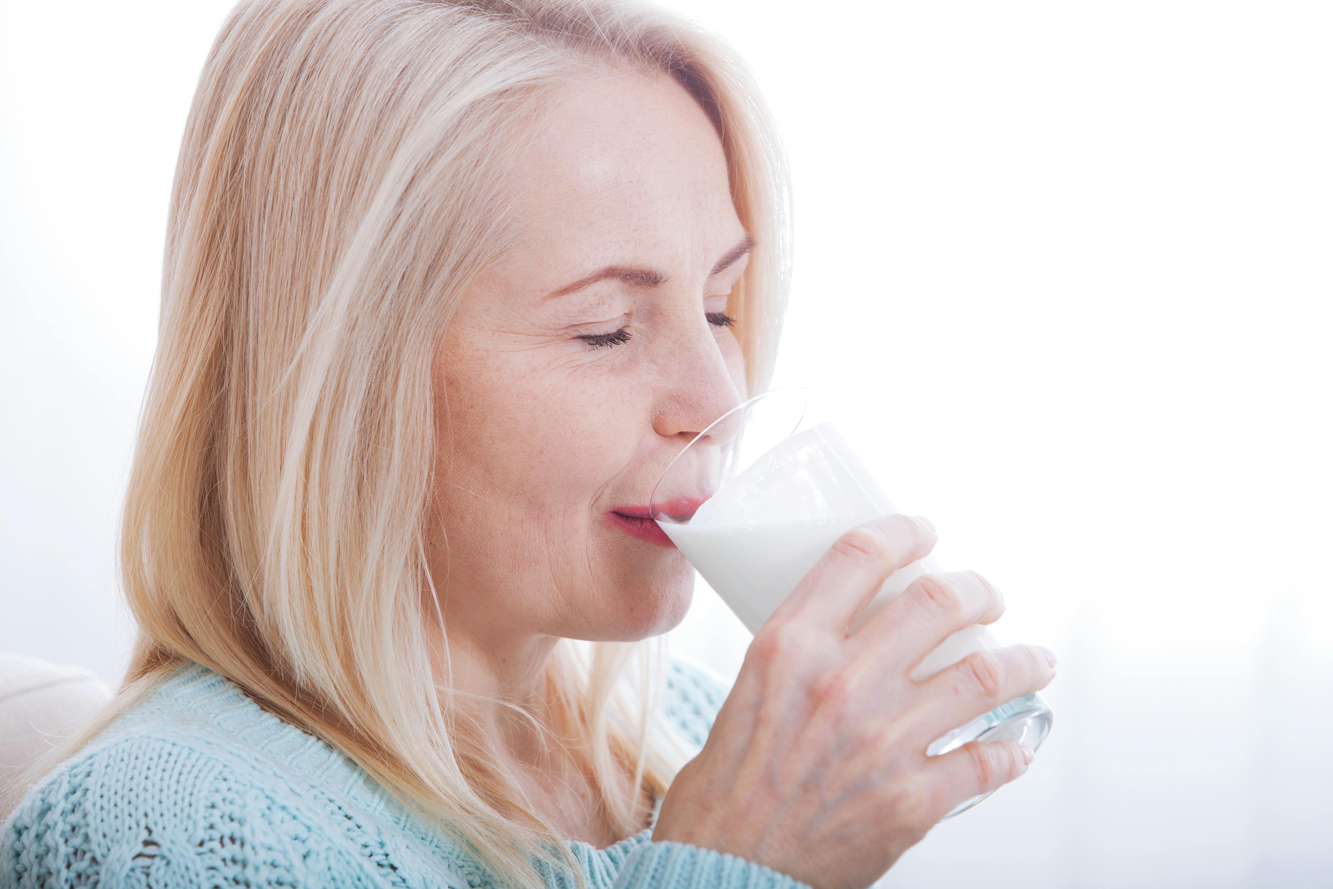 Older woman drinks a glass of milk