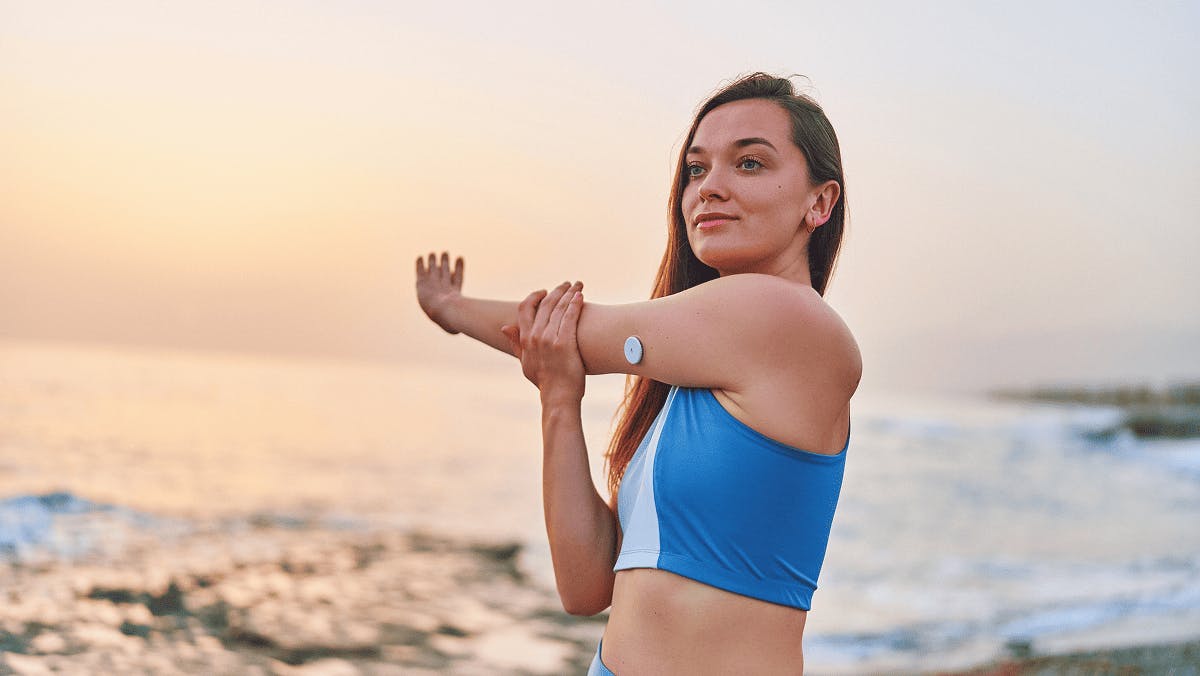 Happy diabetic woman exercising on the beach