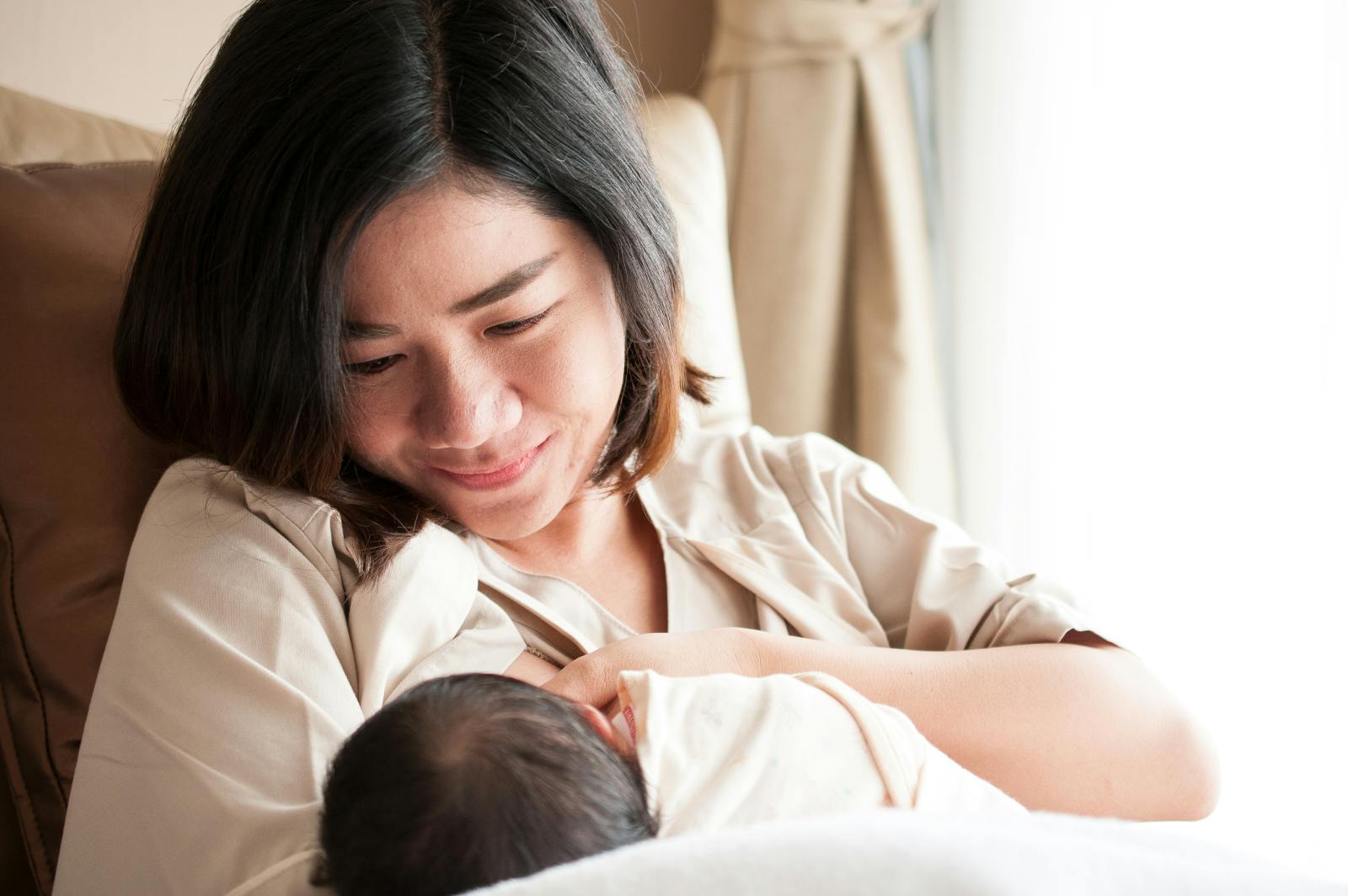 Asian American woman breastfeeds her baby