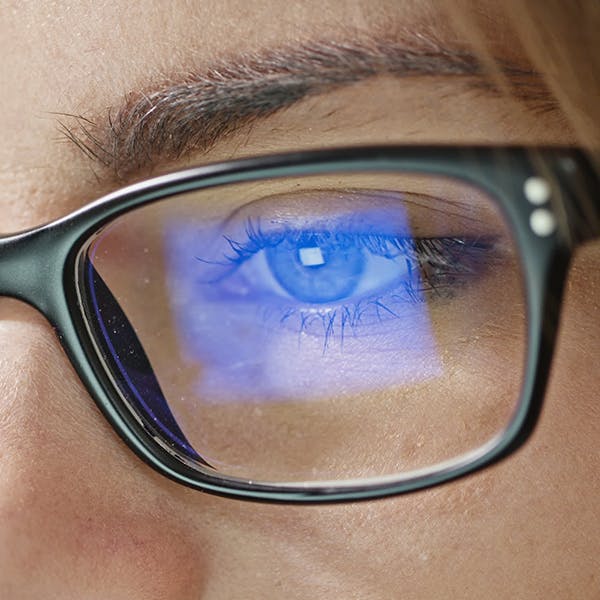 Close up of someone’s eye and glasses with computer screen glare