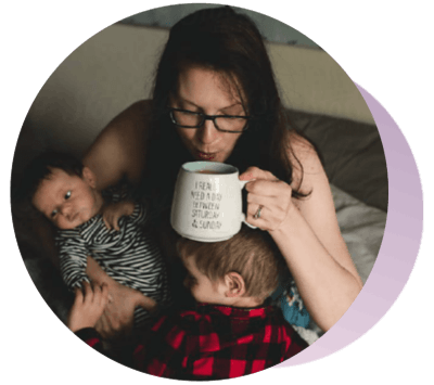 Mujer tomando café en la cama mientras carga a su bebé y a su niño pequeño