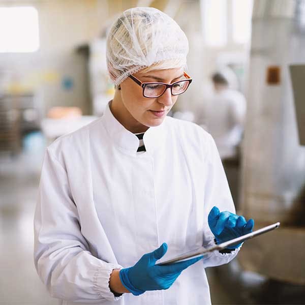 Mujer con traje protector mirando una tableta en el laboratorio