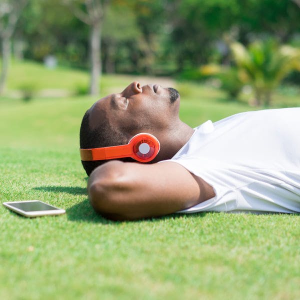 Hombre descansando en un parque usando auriculares