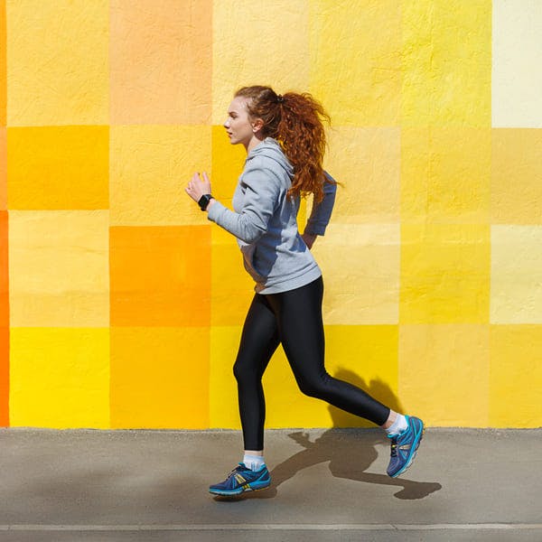 Side view of female athlete running against bright colorful wall
