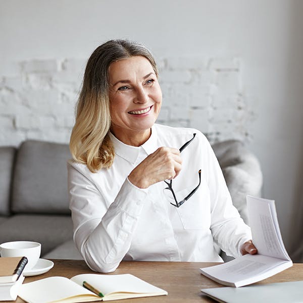 Smiling woman holding her glasses in an office 