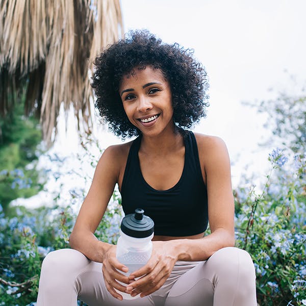 Woman sitting holding a water bottle outside 