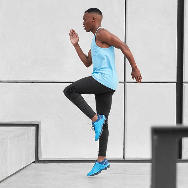 Young man doing high knee exercises in workout clothes