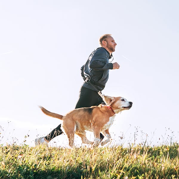 hombre corriendo con su perro al aire libre