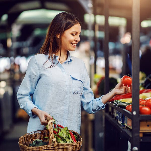 Femme souriante dans un champ avec son panier de récolte