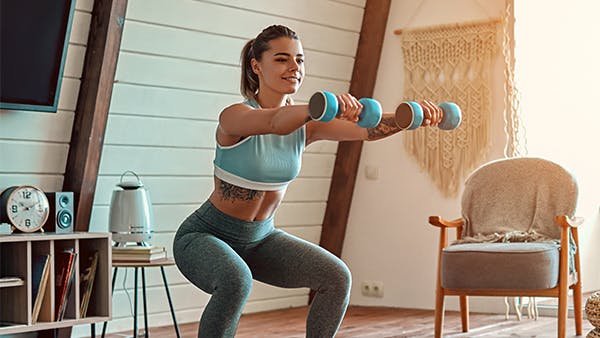 Mujer haciendo ejercicios en cuclillas con pesas