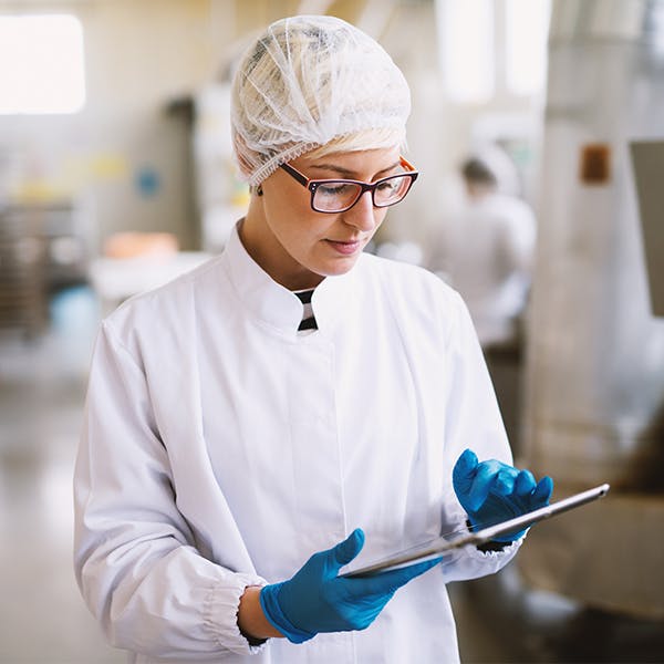 Mujer con equipo de protección revisando un portapapeles en un laboratorio