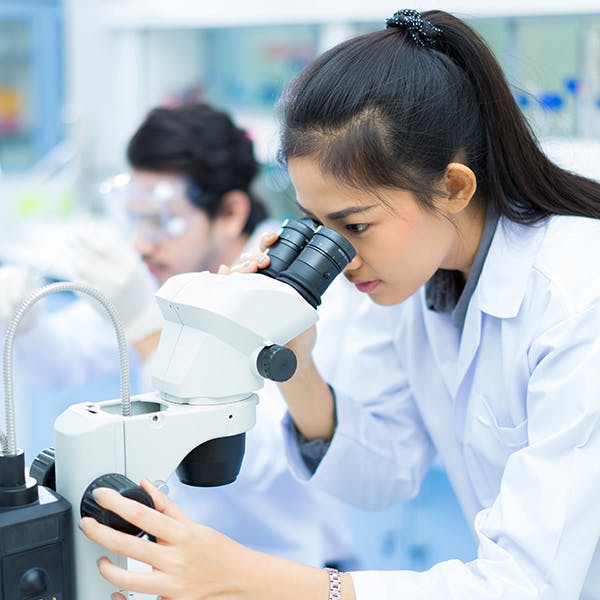 Mujer mirando en un microscopio en un laboratorio.