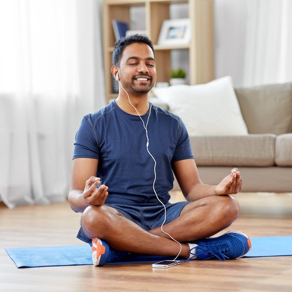 Happy man meditating in his home