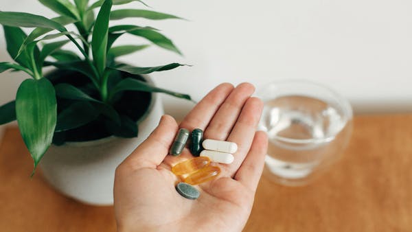 Person holding a handful of multivitamins and supplements. Person holding a handful of multivitamins and supplements.