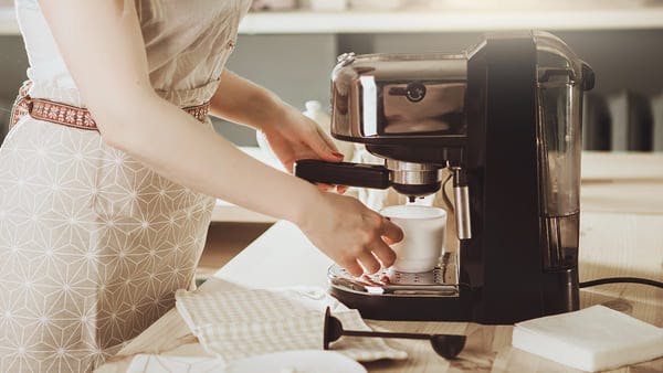 Woman making fresh espresso in coffee maker