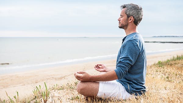 Man sitting on a beach meditating