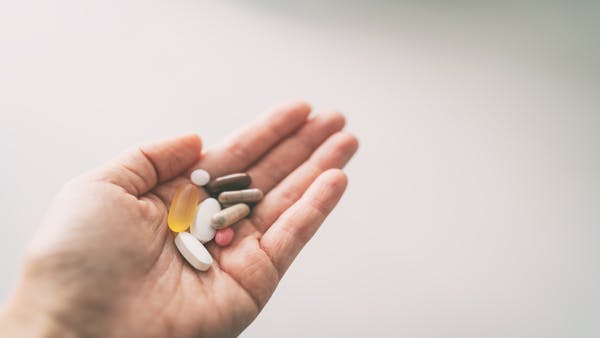 Person holding a handful of multivitamins and supplements.