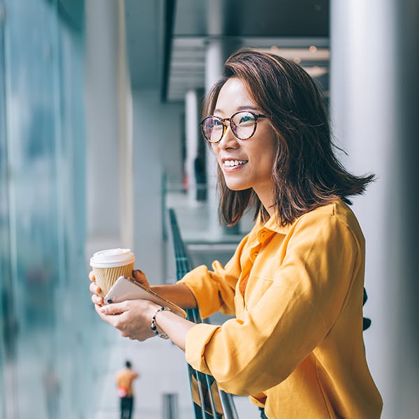 微笑的女人拿着咖啡杯看着外面