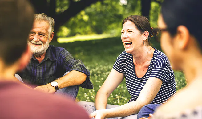 People smiling and laughing while sitting on the grass
