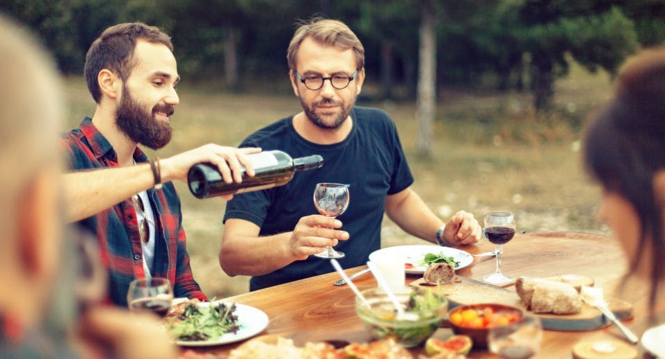 A group of men and women at a table drinking wine