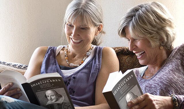 two women reading books and smiling with dentures 