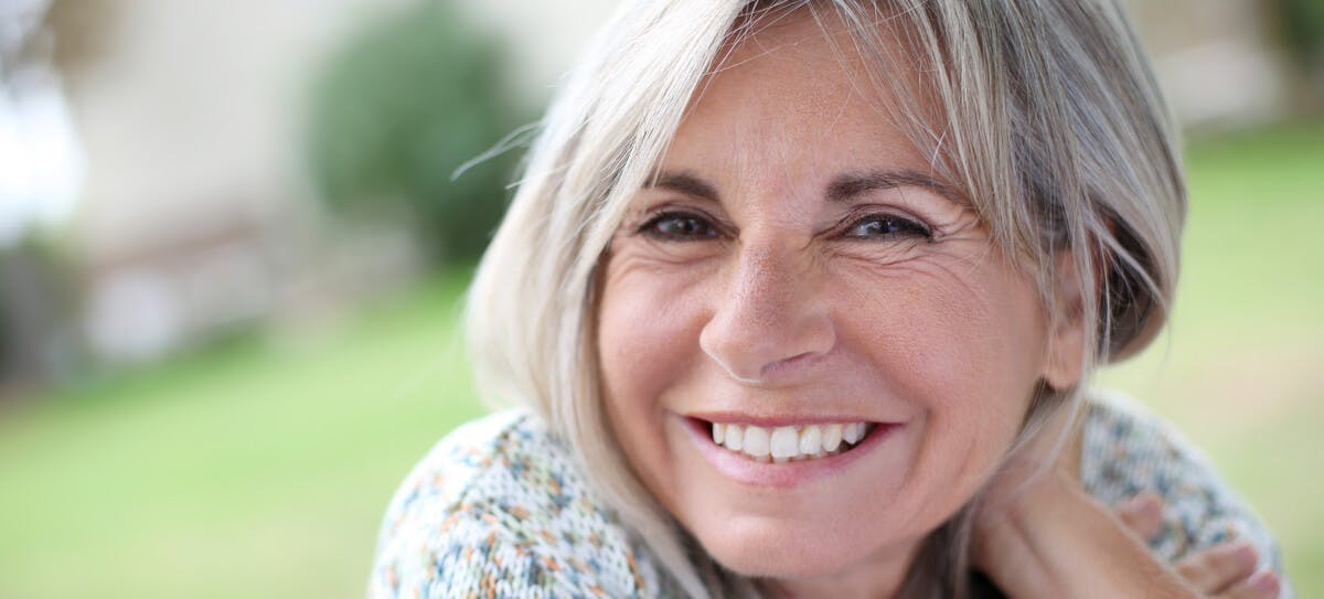 A smiling woman with gray hair who is likely to have candida in her oral microbiome.