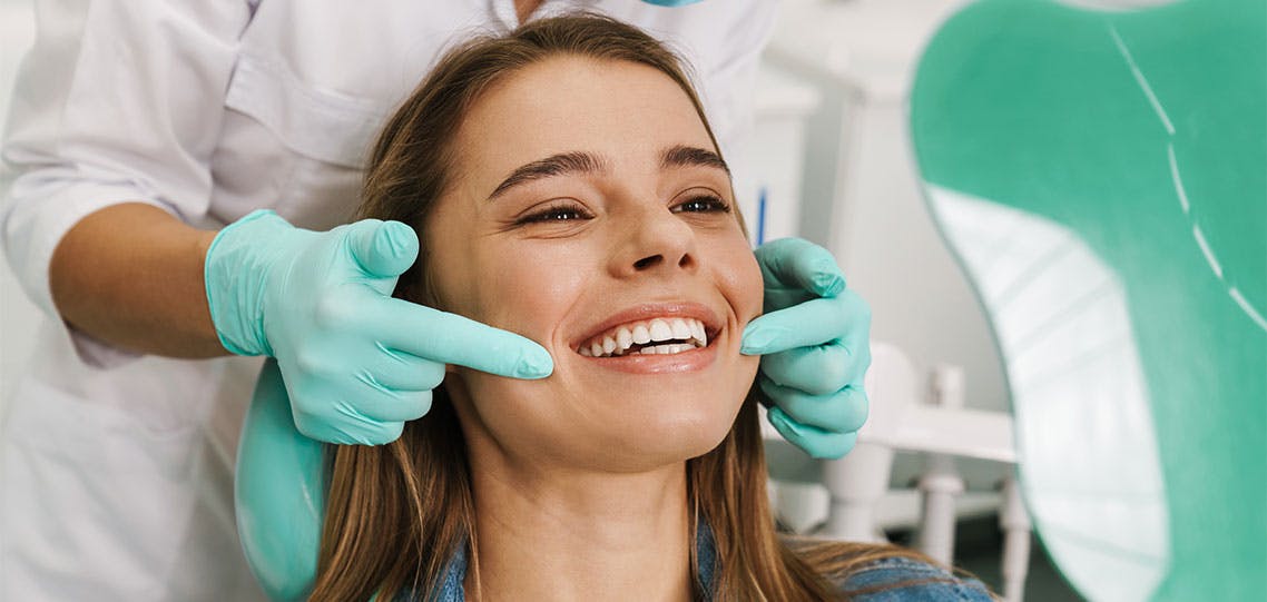 woman smiling while looking at mirror in dental clinic