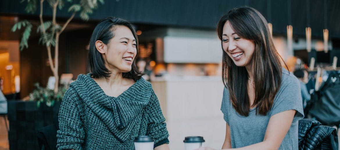 two women laughing over a coffee