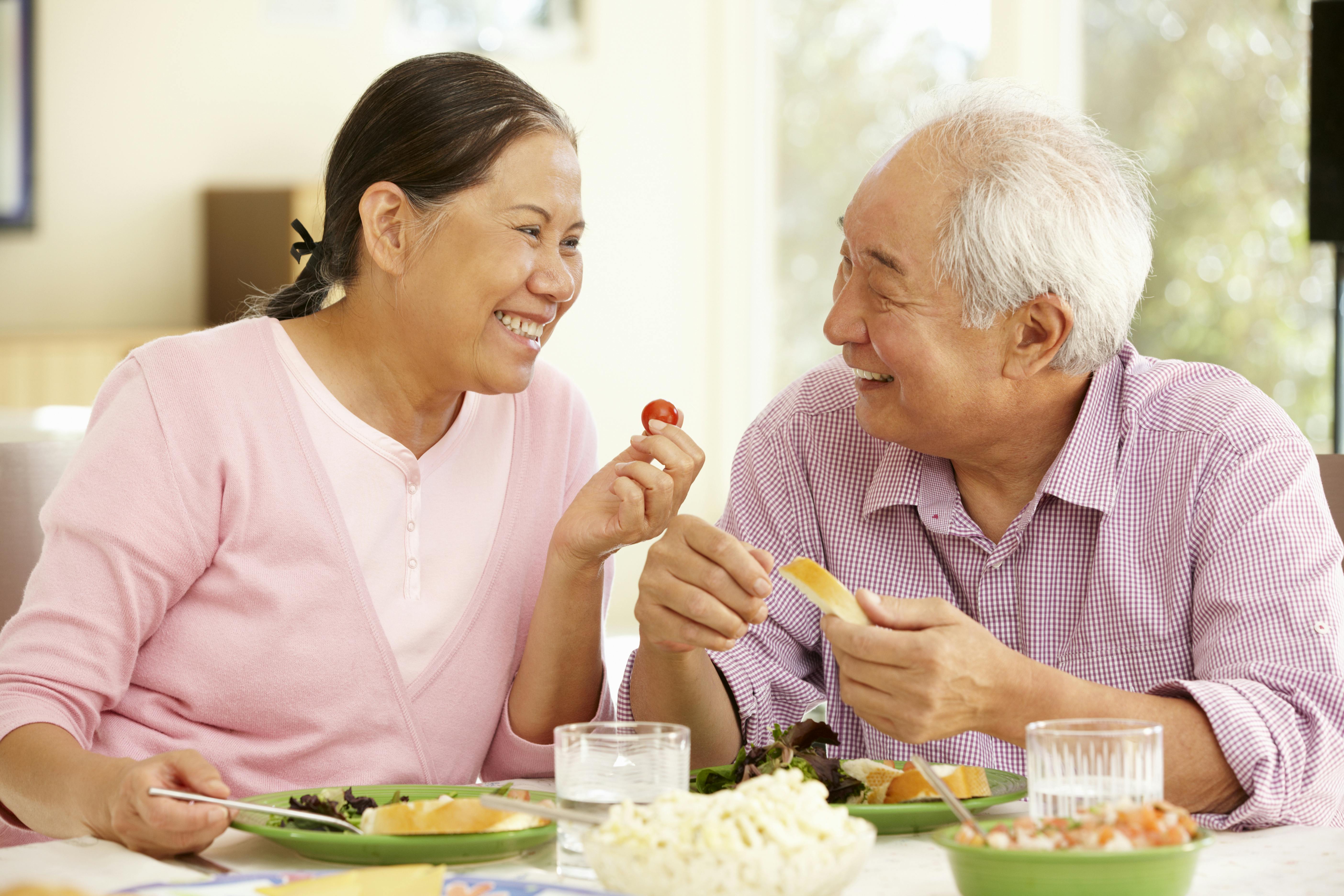 Older couple sharing food together Older couple sharing food together