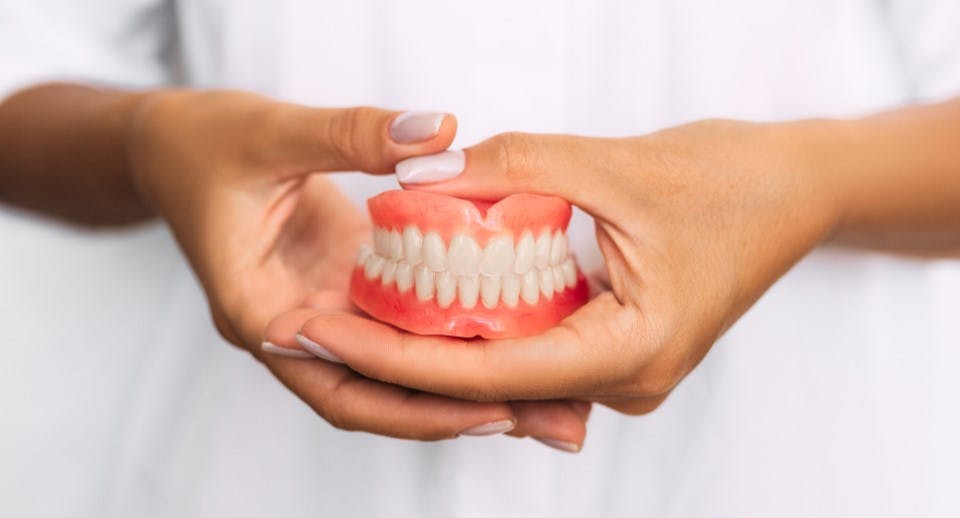 a set of full dentures being held in hands