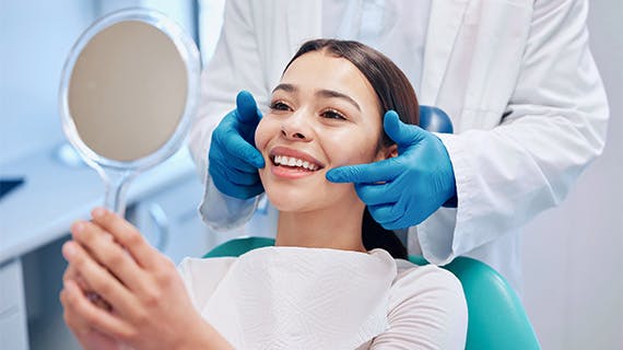 Woman looking in mirror at dentist’s office