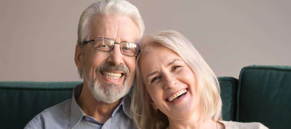 Older couple sits together while smiling and laughing.