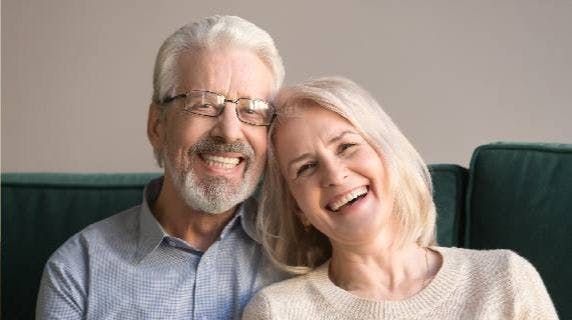 Older couple sits together while smiling and laughing.