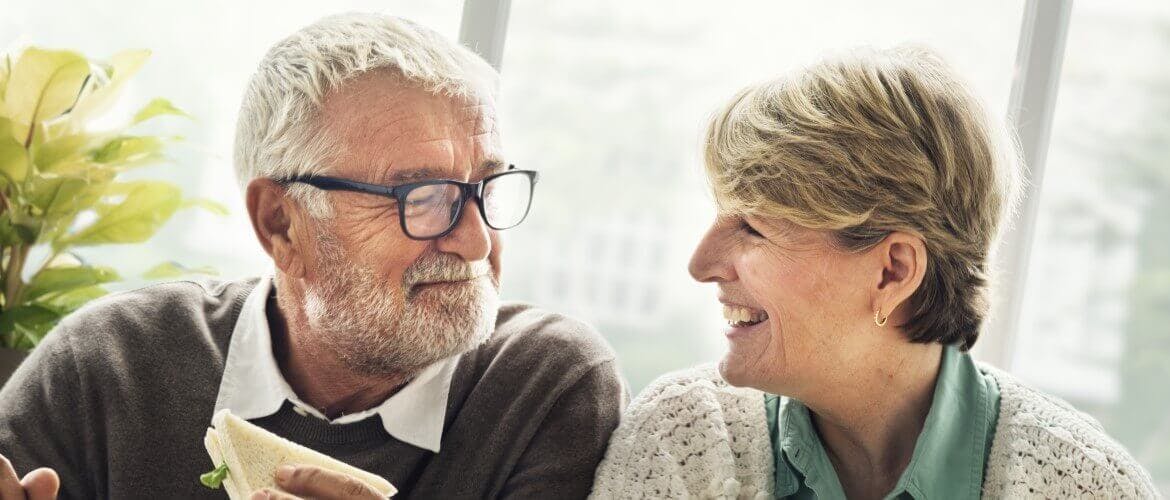 un homme et une femme heureux de manger ensemble avec leur prothèse dentaire et se souriant