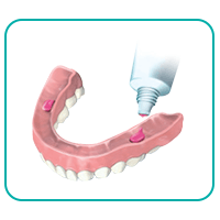 putting adhesive cream on lower dentures