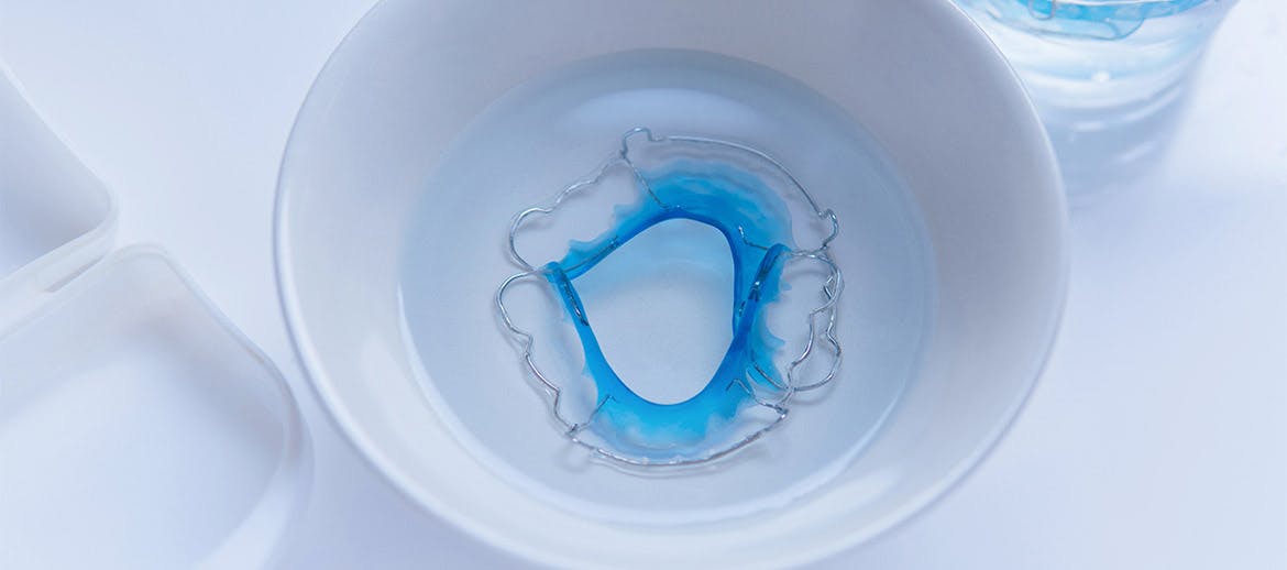 toothbrush cleaning a retainer under water