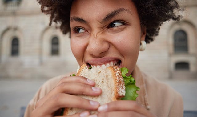 Mujer comiendo un sándwich con dentadura postiza