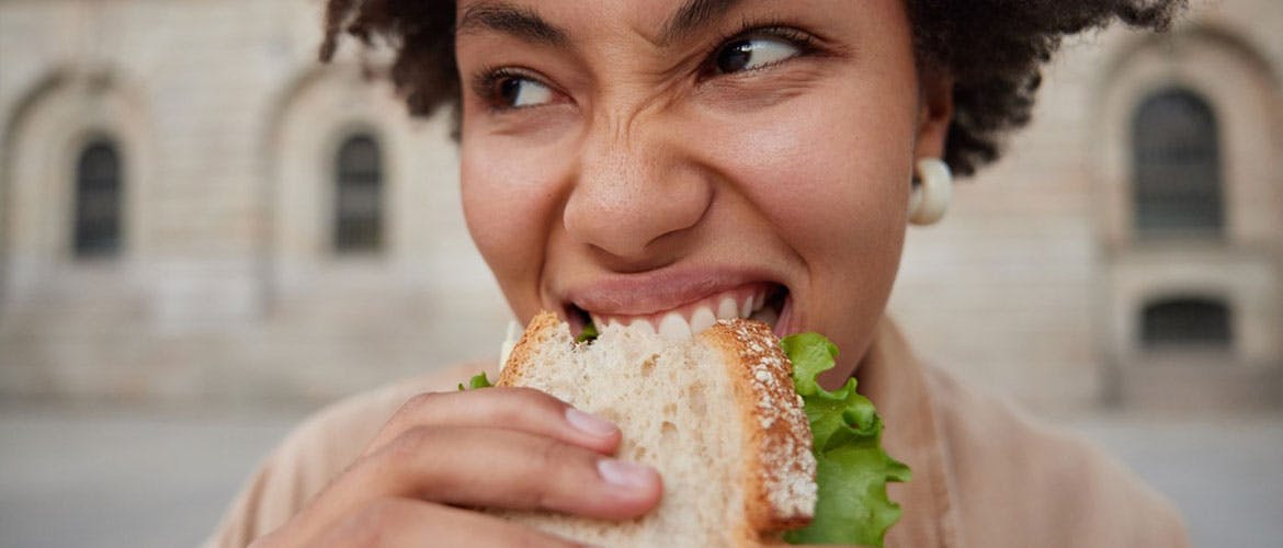 Mujer comiendo un sándwich con dentadura postiza